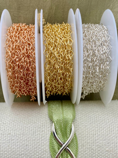 Three metal color options of C56 heart chain displayed on spools