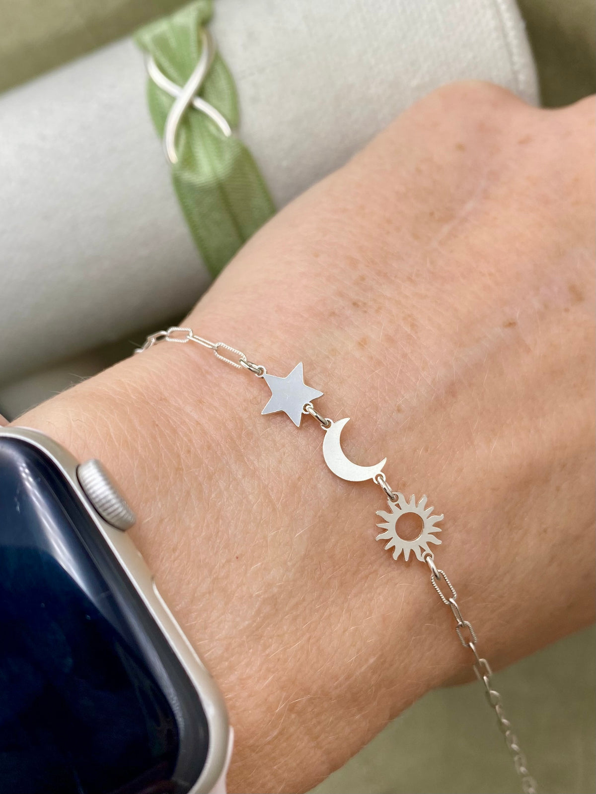 Silver sun connector linked to crescent moon and star connectors in a bracelet worn on wrist