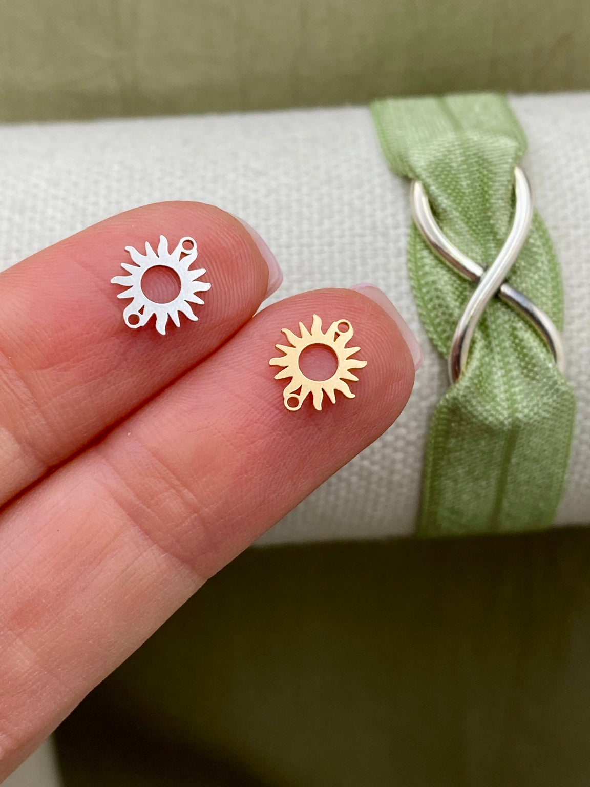 Silver and 14kt gold-filled sun connectors with open centers and rays shown close-up on fingertips